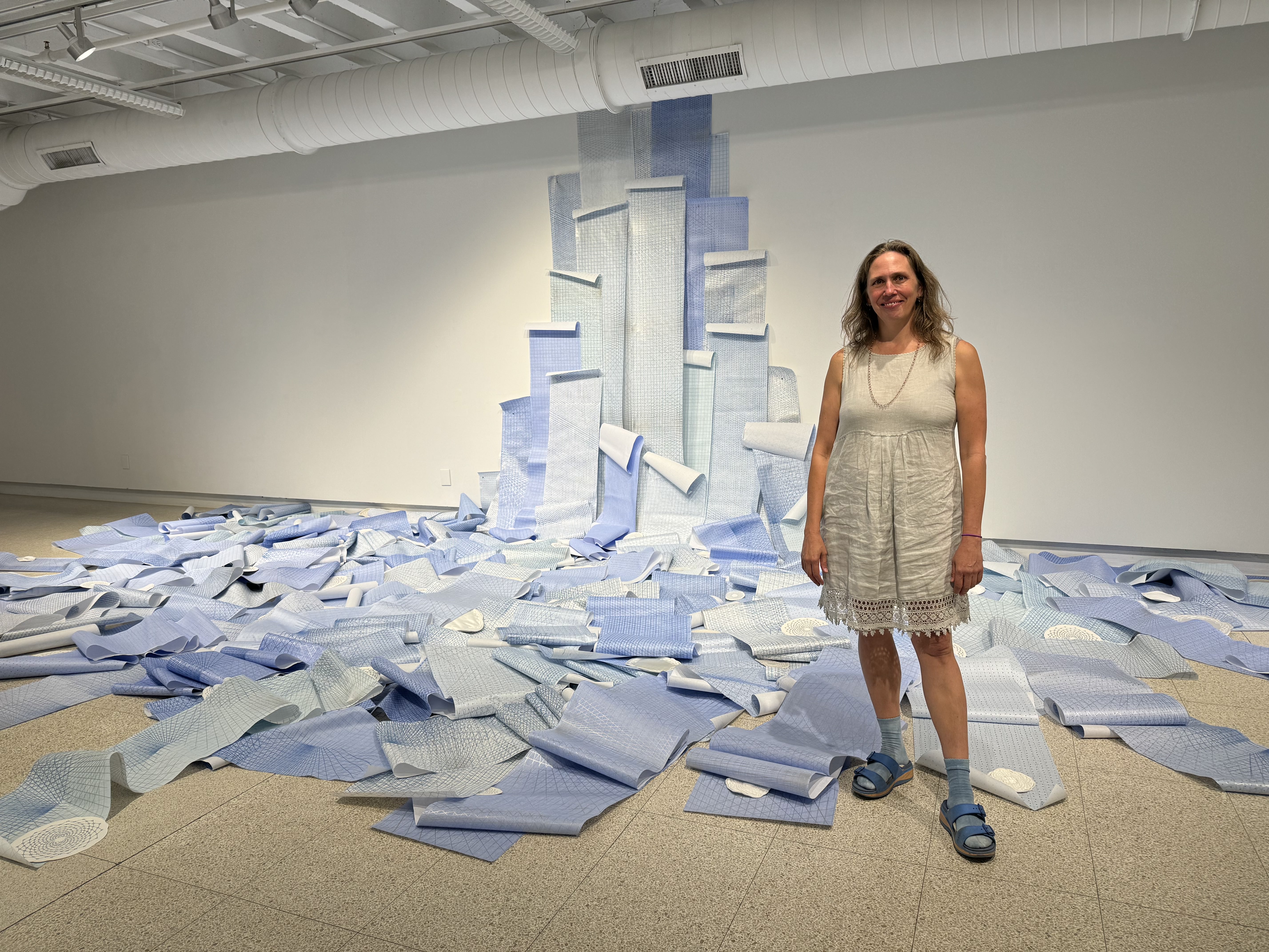 Melissa Haviland standing next to her blue waterfall made from paper