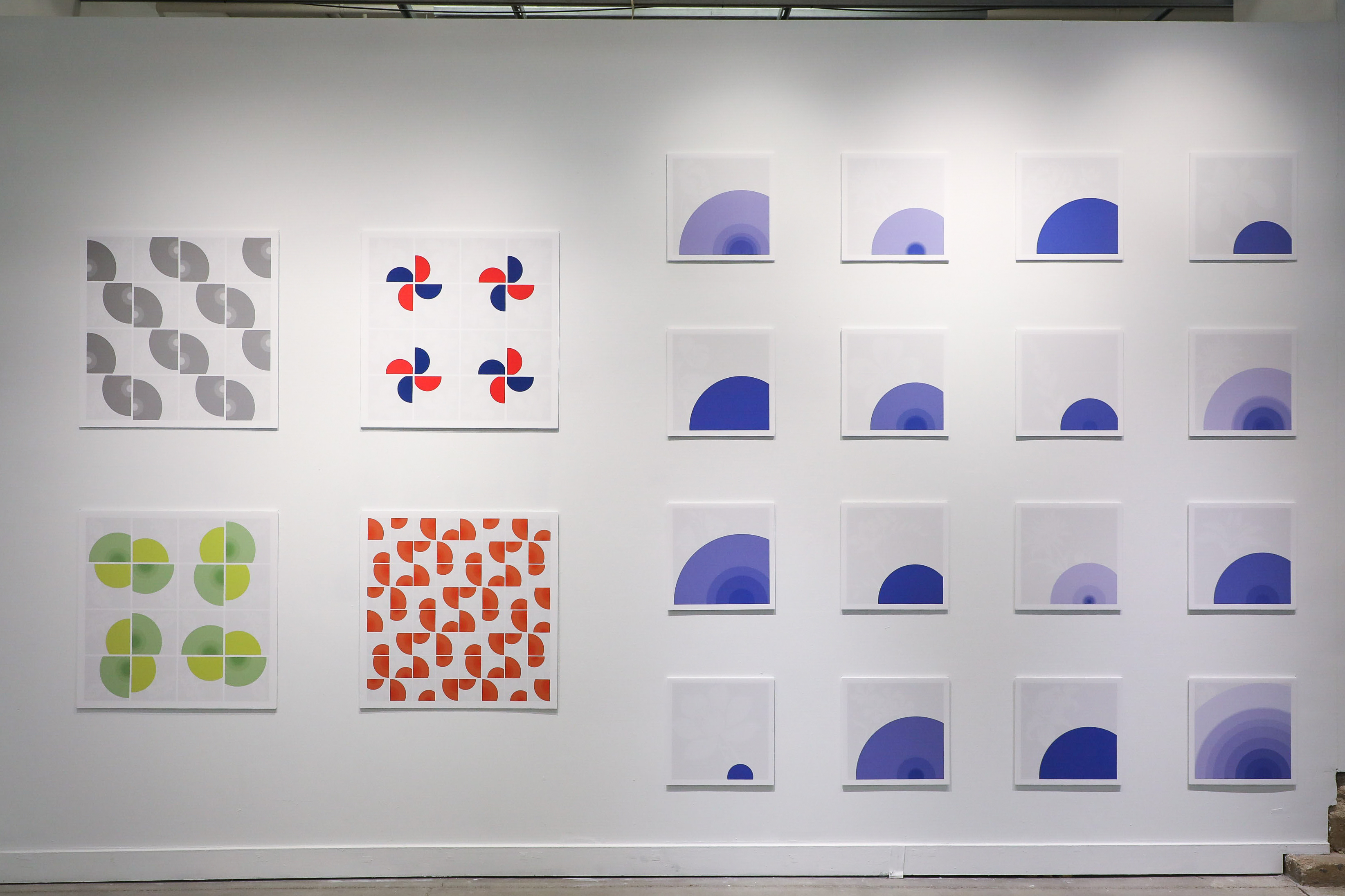 Sixteen-four-by-four white panels line the wall. The panels have blue concentric circles in different sizes printed on them.