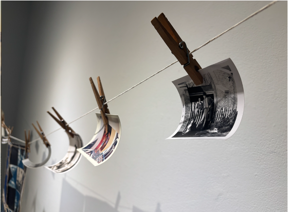 old family photographs hung on a clothesline. The photo in the foreground features a couple and their dog. 