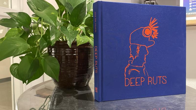 photography book entitled Deep Ruts with a blue cover, next to a plant